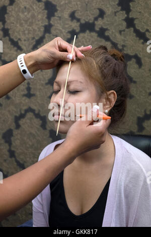 Donne sottoposte a trattamento per sopracciglia per addensare e modellamento in un salone di bellezza England Regno Unito Foto Stock