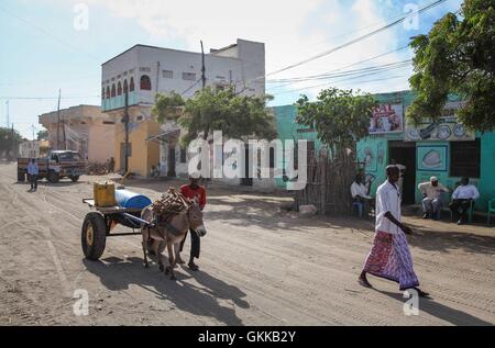 SOMALIA, Kismayo: In un photogaph preso 12 ottobre 2013 e rilasciato dall'African Union-United Nazioni Informazioni sul team di supporto 15 Ottobre, civili somali a piedi giù per una strada durante una pattuglia di soldati del Kenya di servire con la missione dell Unione Africana in Somalia (AMISOM) nella meridionale somala città portuale di Kismayo. Ottobre 16 segna due anni dal Kenya Defence Force primo intervenuto in Somalia sotto il funzionamento Linda Nchi - significato il funzionamento di proteggere il paese in Kiswahili - a seguito di una serie di rapimenti e cross-scorrerie di confine lungo la frontiera Kenya-Somalia da Al Qaeda-te affiliati Foto Stock