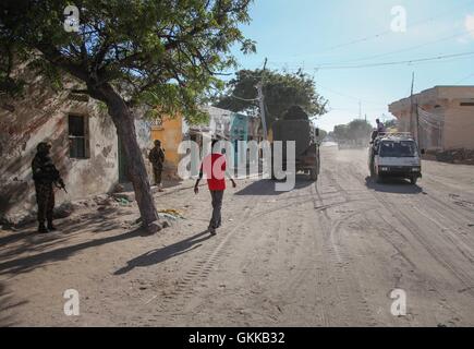 SOMALIA, Kismayo: In un photogaph preso 12 ottobre 2013 e rilasciato dall'African Union-United Nazioni Informazioni sul team di supporto 15 ottobre, un somalo uomo cammina giù per una strada durante una pattuglia di soldati del Kenya di servire con la missione dell Unione Africana in Somalia (AMISOM) nella meridionale somala città portuale di Kismayo. Ottobre 16 segna due anni dal Kenya Defence Force primo intervenuto in Somalia sotto il funzionamento Linda Nchi - significato il funzionamento di proteggere il paese in Kiswahili - a seguito di una serie di rapimenti e cross-scorrerie di confine lungo la frontiera Kenya-Somalia da Al Qaeda-terro affiliati Foto Stock