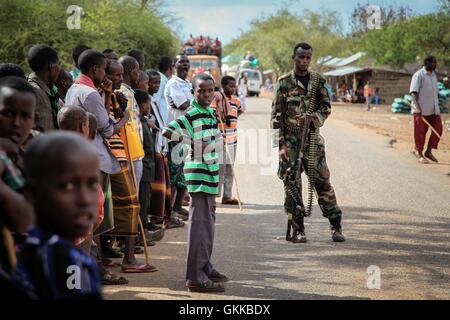 SOMALIA, Modmoday: In una fotografia scattata il 15 ottobre e rilasciato dall'African Union-United Nazioni Informazioni sul team di supporto 24 ottobre, i residenti del villaggio di Modmoday, guardare come un soldato del somalo Esercito Nazionale (SNA) mantiene la guardia, circa 40km ad est del centro città somala di Baidoa. Truppe burundesi di servire con la missione dell Unione Africana in Somalia (AMISOM) insieme con le forze di SNA sono stati il montaggio 'snap' pattuglie a piedi nei villaggi e nelle zone ad est di Baidoa dove Al Qaeda affiliate del gruppo estremista al Shabaab sferrare attacchi contro i pastori locali, villaggi e trave Foto Stock