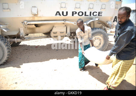 I beneficiari di una dispensa alimentare a un IDP camp, Siliga Amerikanka, il 24 febbraio 2014 il trasporto di un sacco di granturco. Un gruppo di singole forze di polizia AMISOM ufficiali alcune raccolte di denaro tra di loro e hanno comprato i prodotti alimentari per una comunità di 50 persone non vedenti. Foto Stock