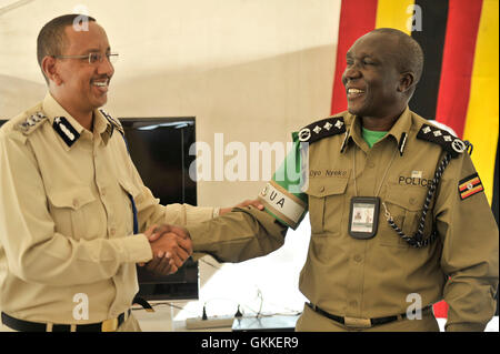 Somali commissario di polizia, Gen. Abdihakim Saacid e AMISOM Assistente commissario di polizia, Benson Oyo-Nyeko agitare le mani durante una medaglia cerimonia di premiazione per l Uganda formato unità di polizia di polizia il 9 luglio 2014 a Mogadiscio Stadium. Le medaglie sono stati aggiudicati a 138 agenti di polizia, uomini e donne che si avvicina al completamento della loro distribuzione per la Somalia. AMISOM foto / David Mutua Foto Stock