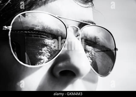 Ragazzo adolescente con ponte di mirroring in occhiali da sole. Tema estivo. Ritratto di giovane. Foto in bianco e nero. Foto Stock