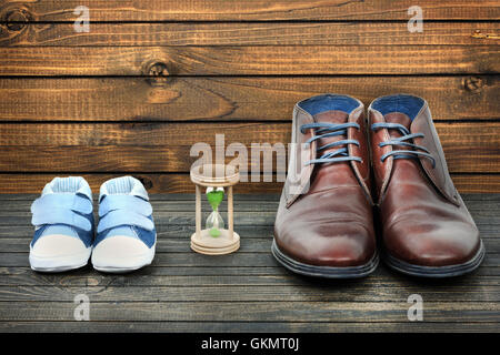 Crescere concetto con kid scarpe e calzature di business su pavimento in legno Foto Stock