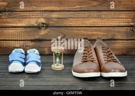 Crescere concetto con kid scarpe e calzature di business su pavimento in legno Foto Stock