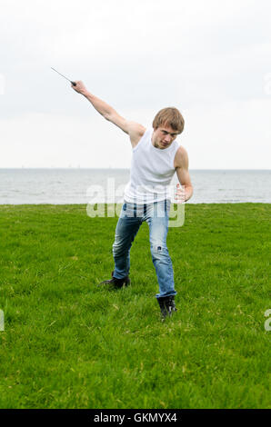 Uomo con coltello militare in riva al mare Foto Stock