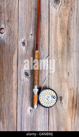 Vista superiore dell'antiquariato canna da mosca e aspo su rustiche tavole in legno in formato verticale. Foto Stock