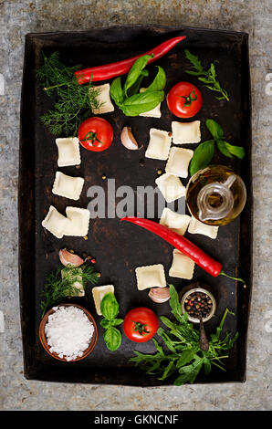 Ravioli con erbe e verdure per la cottura su un vecchio sfondo scuro. Vista superiore Foto Stock
