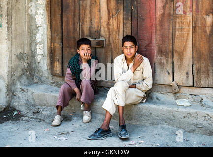 Due giovani uomini pakistano seduto davanti a un negozio chiuso sulla Karakoram Highway nel nord del Pakistan Foto Stock