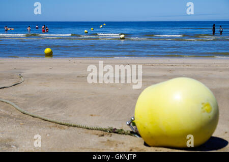 Boe galleggianti sulla spiaggia di Trouville in Francia. Parte del giallo le boe di segnalazione fine fino a terra durante la bassa marea. Foto Stock