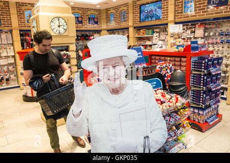 Divertente,royalty,i, Regina, saluta i turisti al tourist shop outlet "glorioso Gran Bretagna' regali. Aerostazione partenze, l'aeroporto di Stansted, Londra,U.K. Foto Stock