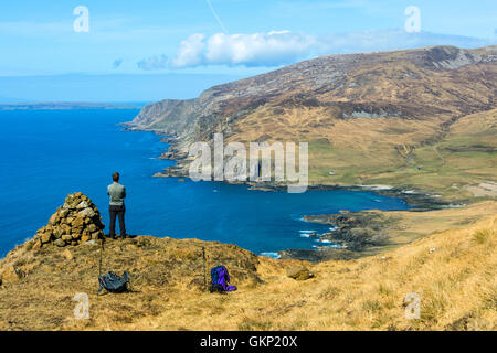 Un viandante sulla via costiera sotto Ruinsival nelle montagne Coullin, guardando verso il basso sulla baia di Harris, Isola di Rum, Scotland, Regno Unito Foto Stock