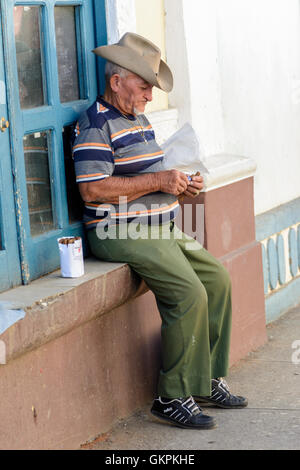 Un cubano di uomo si siede su un davanzale vendita di sigari in Trinidad, Sancti Spiritus provincia, Cuba Foto Stock