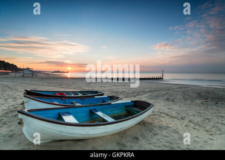 Bellissima alba su barche sulla spiaggia a Durley Chine in Bournemouth con il molo in lontananza Foto Stock