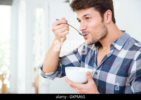 Bel giovane in plaid shirt avente la colazione a casa Foto Stock