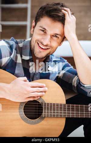Felice bel giovane in plaid shirt tenendo la chitarra Foto Stock