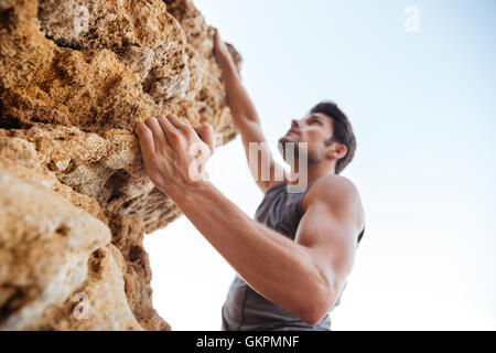 Bruna giovane uomo naturale di arrampicata parete rocciosa Foto Stock