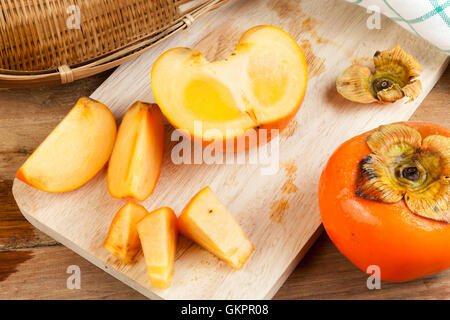 Persimmon colore giallo maturi frutti diviso sulla tavola di legno Foto Stock