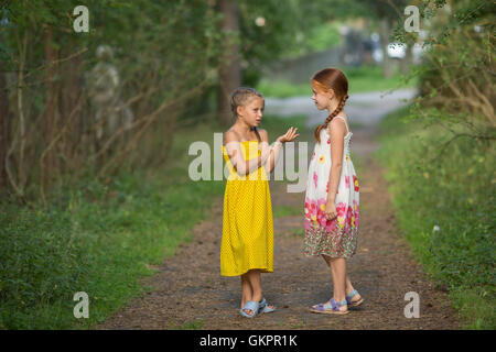 Due bambine parlando simpatici amici in piedi in vicolo. Foto Stock