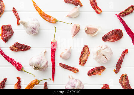 Aglio e pomodori secchi e peperoni sul tavolo bianco. Vista dall'alto. Foto Stock