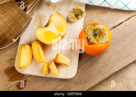 Persimmon colore giallo maturi frutti diviso sulla tavola di legno Foto Stock