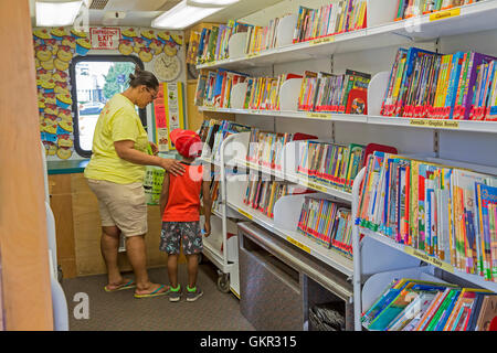 Detroit, Michigan - Un ragazzo cerca un libro in Detroit Public Library 'Libreria su ruote' durante un estate street fair. Foto Stock