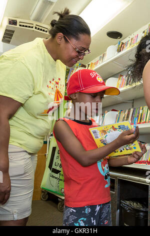 Detroit, Michigan - Un ragazzo cerca un libro in Detroit Public Library 'Libreria su ruote' durante un estate street fair. Foto Stock