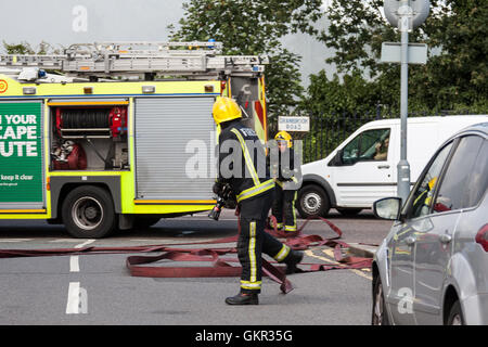 Vigili del fuoco impostazione di un approvvigionamento di acqua da un idrante durante un incendio in un albergo nella zona est di Londra Foto Stock