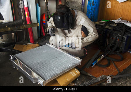 I thailandesi utilizzano l'elettricità di saldatura per fissare e saldare il radiatore di auto in garage locale a Nonthaburi, Tailandia Foto Stock