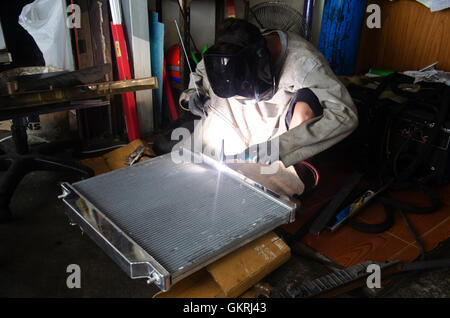I thailandesi utilizzano l'elettricità di saldatura per fissare e saldare il radiatore di auto in garage locale a Nonthaburi, Tailandia Foto Stock