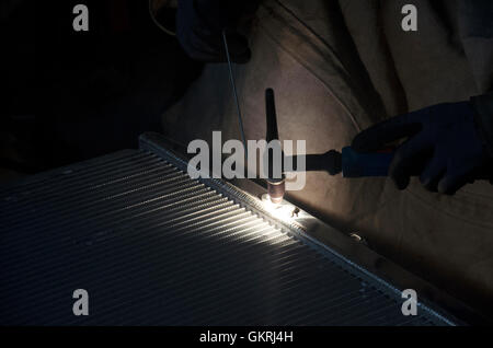 I thailandesi utilizzano l'elettricità di saldatura per fissare e saldare il radiatore di auto in garage locale a Nonthaburi, Tailandia Foto Stock