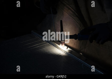 I thailandesi utilizzano l'elettricità di saldatura per fissare e saldare il radiatore di auto in garage locale a Nonthaburi, Tailandia Foto Stock