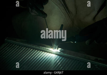 I thailandesi utilizzano l'elettricità di saldatura per fissare e saldare il radiatore di auto in garage locale a Nonthaburi, Tailandia Foto Stock