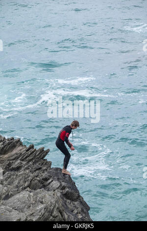 Un adolescente tombstoning off a strapiombo sul promontorio in Newquay, Cornwall. Foto Stock