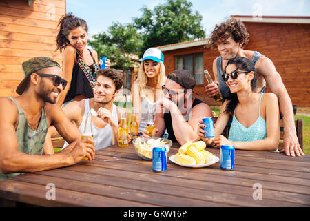 Ritratto di Allegro giovani amici di ridere e di aver parte alla tabella all'aperto Foto Stock