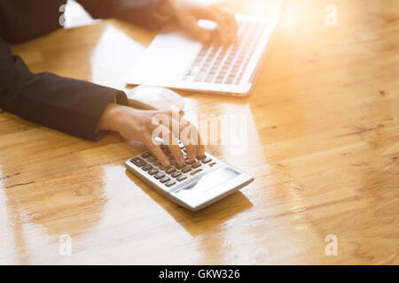 Contabile che lavora con la calcolatrice e computer laptop sulla scrivania in ufficio Foto Stock