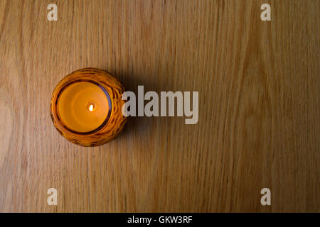 Un piccolo tea candela luce in arancione jar, luce di contrasto, chiudere e vista dal cielo Foto Stock
