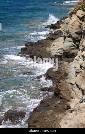 Delle onde dell'oceano urtare contro una roccia Foto Stock