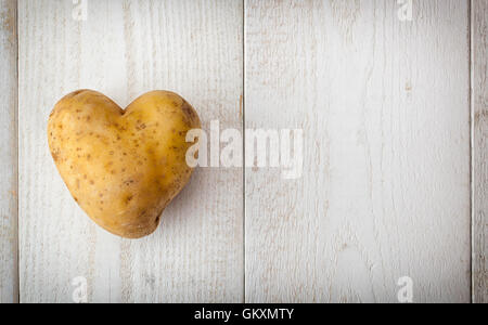 A forma di cuore sulla patata bianca tavolo in legno. Foto Stock