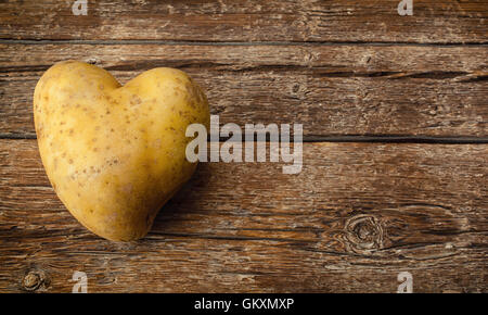 A forma di cuore sulla patata in legno scuro tavolo. Foto Stock