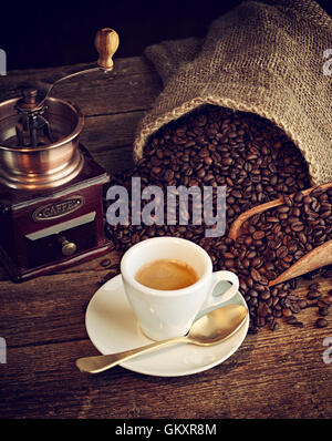 Tazza di caffè espresso, i chicchi di caffè e vecchio macinino da caffè sul tavolo di legno. Foto Stock