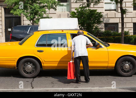 Un uomo chiede informazioni ad un tassista di Manhattan. Il taxicabs di New York City sono ampiamente riconosciute icone della città. Foto Stock