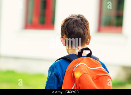 Ragazzo con zaino in spalla davanti a un edificio scolastico Foto Stock