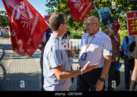 Londra, Regno Unito. 23 Agosto, 2016. Un ufficiale di pattuglia da Lambeth South Bank Patrol team comunica Peter Kavanagh, unite a Londra il segretario regionale che i membri dell'Unite Hotel lavoratori filiale lanciando la loro immorale rapporto di Londra non è permesso di esporre cartelli e striscioni in Jubilee Gardens. Credito: Mark Kerrison/Alamy Live News Foto Stock