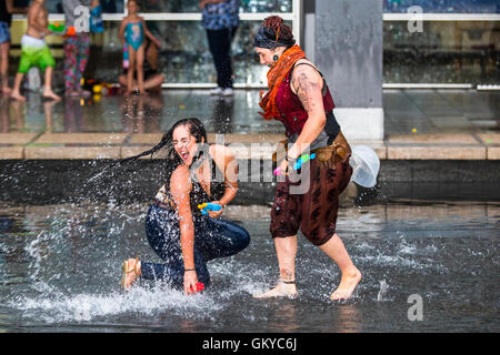 Bristol, Regno Unito. 24 Agosto, 2016. Un massiccio acqua lotta ha avuto luogo a Bristol's Millennium Square questa sera. Decine di persone hanno utilizzato le pistole ad acqua, bottiglie, palloncini e benne per attaccare ogni altro con acqua. Avon e Somerset Vigili del Fuoco sono arrivati con un motore Fire a partecipare. Hanno partecipato anche il Bristol l' ex-eletto sindaco, George Ferguson. L evento è stato organizzato per raccogliere fondi per un senzatetto YMCA hostel. Bristol, Regno Unito. 24 agosto 2016. Credito: Fotografia Redorbital/Alamy Live News Foto Stock