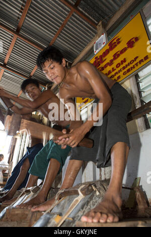Un team di uomini birmani beat oro a re Galon Workshop a Mandalay, Myanmar (Birmania). Essi creare fogli di lamina d'oro. Foto Stock