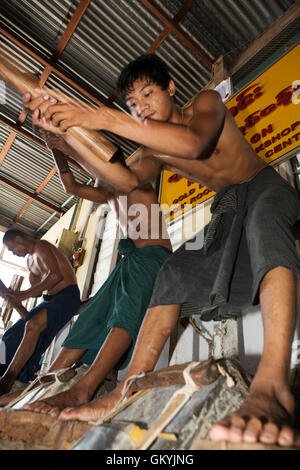 Un team di uomini birmani beat oro a re Galon Workshop a Mandalay, Myanmar (Birmania). Essi creare fogli di lamina d'oro. Foto Stock