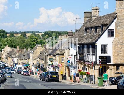 Vista dei negozi lungo la collina via dello shopping durante la stagione estiva, burford, Oxfordshire, Inghilterra, Regno Unito. Foto Stock