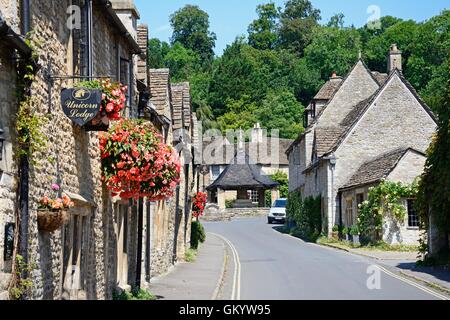 Vista lungo il villaggio principale street verso il quattordicesimo secolo croce di mercato nel centro del villaggio, Castle Combe, Inghilterra. Foto Stock