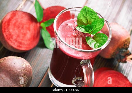 Succo di barbabietola con foglioline di menta e barbabietole sparse su sfondo di legno Foto Stock